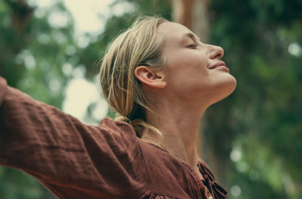 Mujer en paz disfrutando de un momento de sanación emocional y energética al aire libre