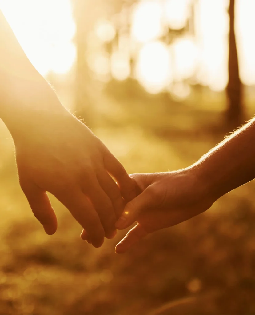 Manos entrelazadas al atardecer como símbolo del vínculo restaurado en el programa de sanación emocional para parejas Sanando Juntos