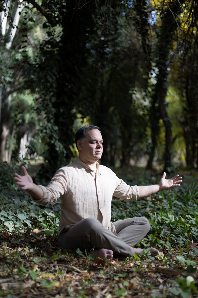 Mauricio Fracapani meditando con los brazos abiertos en el bosque, facilitando espacios sagrados de autosanación y conexión energética